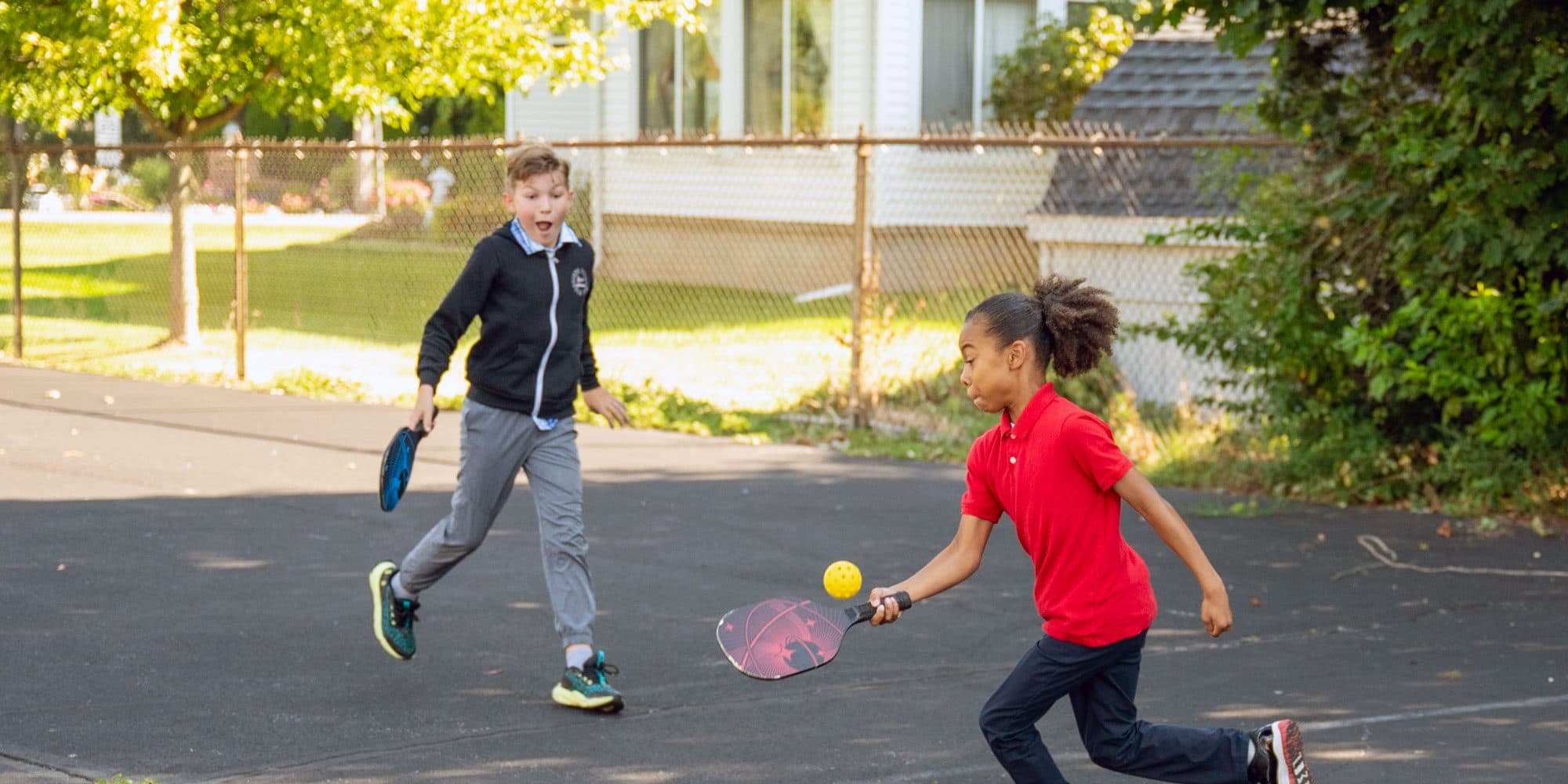 Two students playing pickleball on an outdoor court.