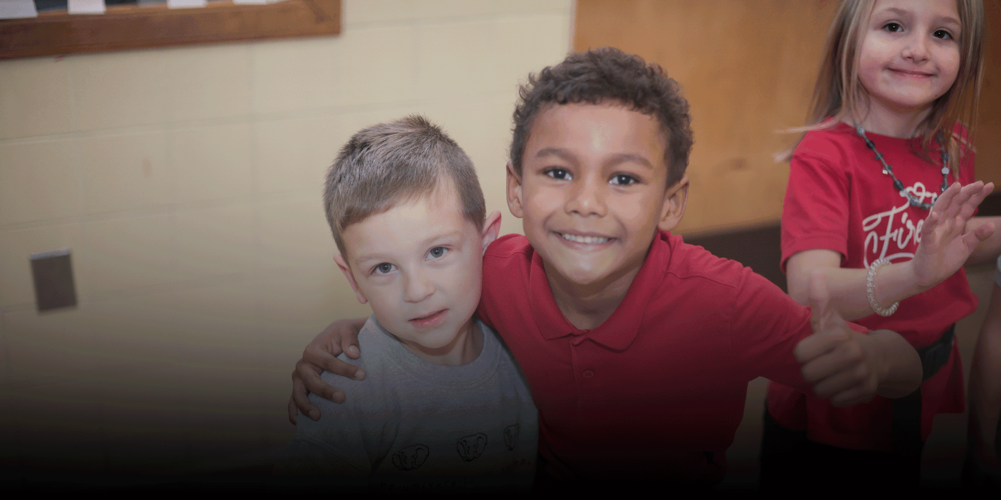 Three students smiling and posing together, one giving a thumbs up.